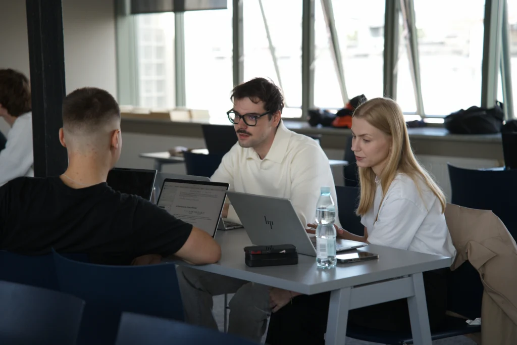 Oskar Janicki, Jakub Góral i Wiktoria Klimek w trakcie pracy zespołowej siedzący przy biurku z laptopami na czwartym zjeździe SDGI 12.06.2026
