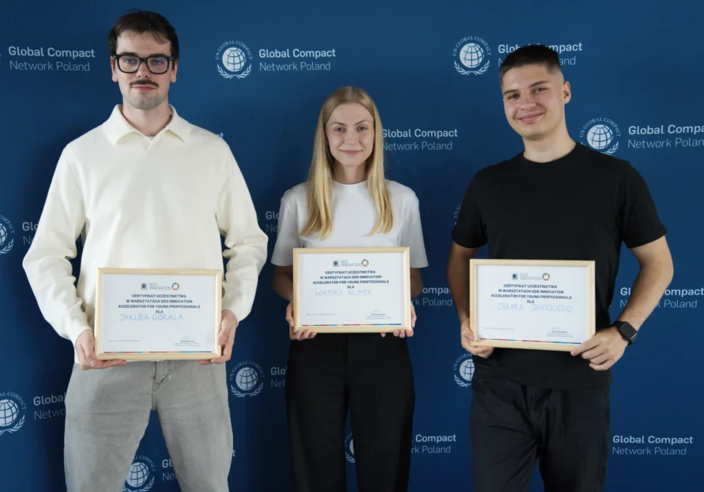 Jakub Góral, Wiktoria Klimek i Oskar Janicki stojący na tle ścianki UNGC i trzymający w ręce certyfikaty uczestnictwa w SDGI od UNGC na czwartym, finałowym zjeździe SDGI 12.06.2026